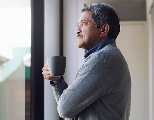 Man drinking a coffee and looking out of a window