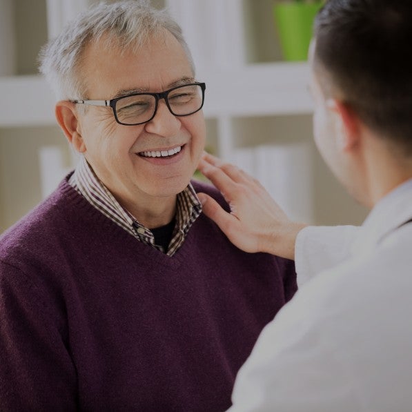 A doctor putting their hand on an older patient's shoulder