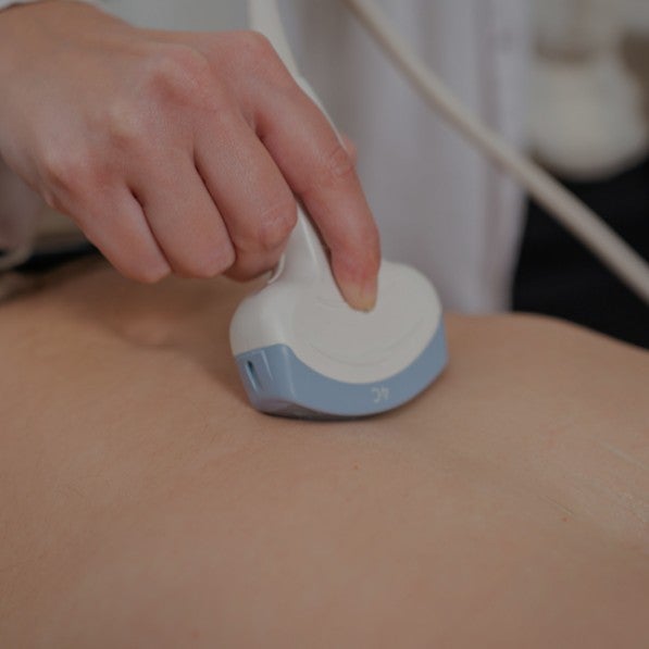 A doctor using a device to scan a patient's stomach