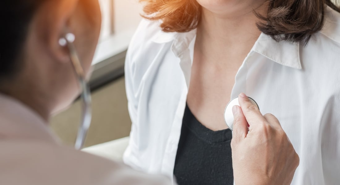 Doctor checking female patient with stethoscope