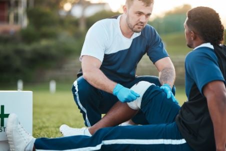 Athletic Trainer Helping Athlete on Ground